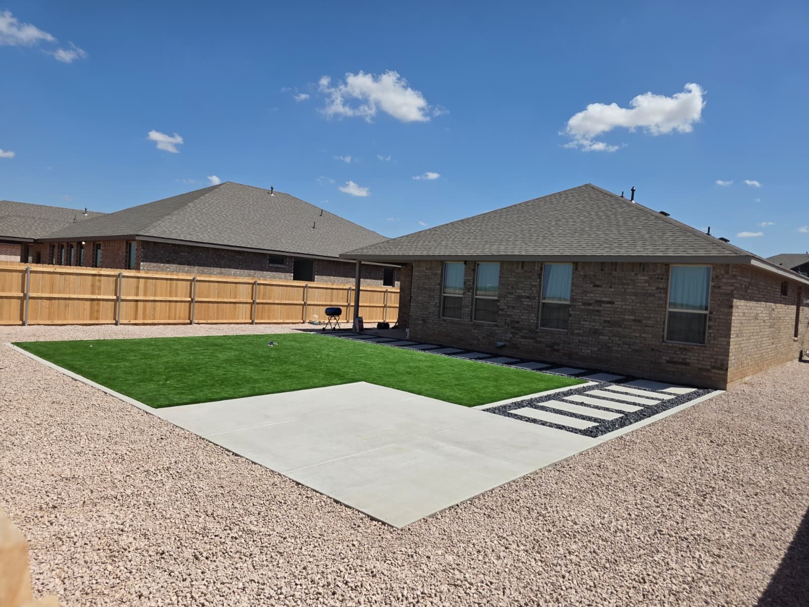 Modern dry garden design featuring artificial grass, a stepped stone path, gray gravel accents, and a beige gravel area.